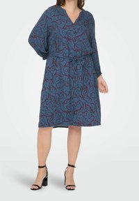 Sininen mekko, jossa on burgundin värinen kukkakuosi, V-pääntie, pitkähihaisuus ja vyö vyötäröllä. Tasainen kankaan pinta.
