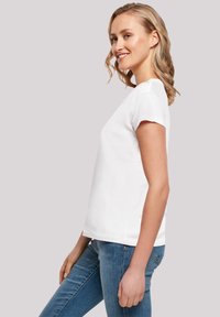 White cotton t-shirt with short sleeves and a crew neckline, featuring a relaxed fit and a smooth texture, paired with blue denim jeans.