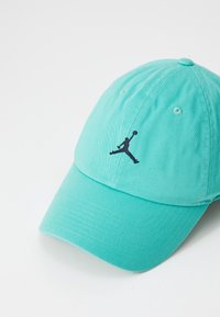 Türkise Baseballmütze aus Baumwolle mit einem gebogenen Schirm. Verfügt über ein schwarzes Jumpman-Logo, das auf der Vorderseite gestickt ist.