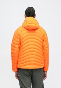 Oransje dunjakke med kviltedesign, hette og elastiske mansjetter. Materialet ser lettvekts ut med en glatt tekstur.