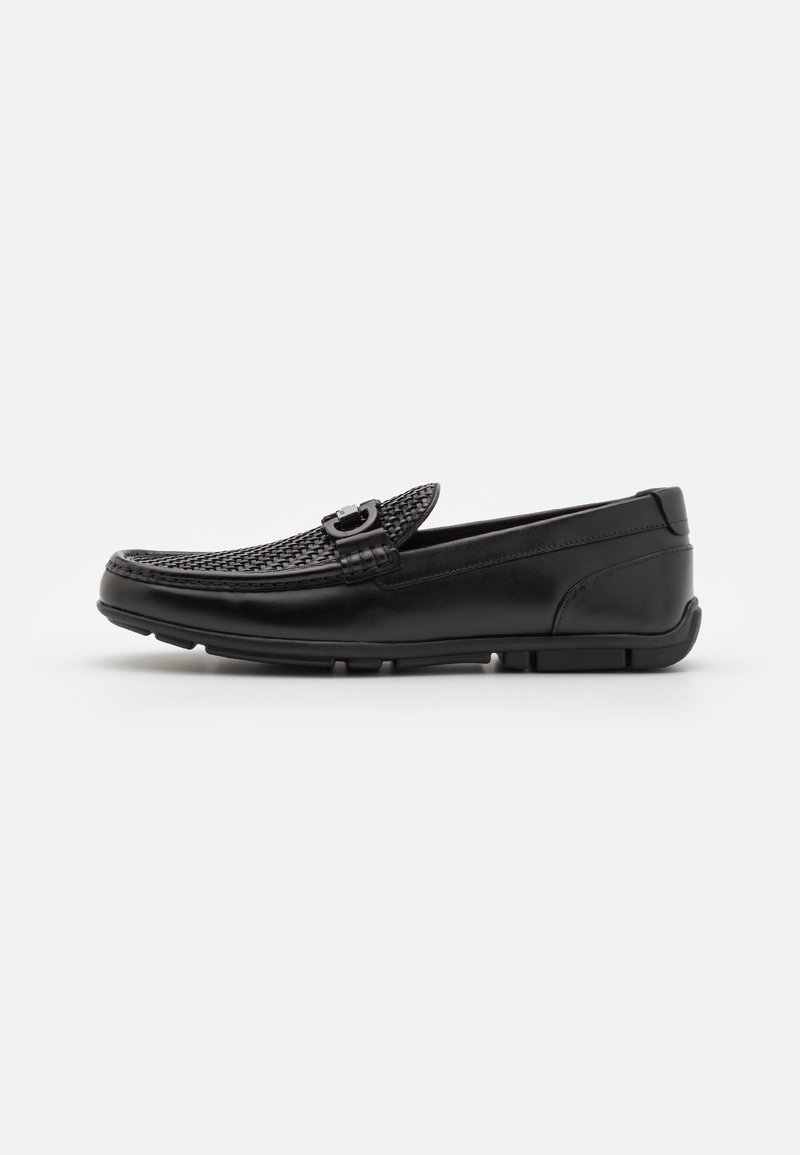 Mocassin en cuir noir avec empeigne tissée, détail boucle métallique et semelle en caoutchouc, vu de côté gauche sur fond blanc.