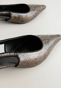Chaussures à talons hauts en cuir synthétique avec un motif serpent brun et noir, à bout pointu et côtés ouverts, avec une texture lisse et une doublure intérieure noire.