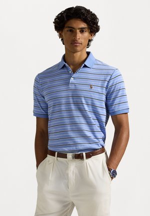 Svetlomodrá polo tričko s bielymi a námorníckymi pruhmi, krátke rukávy a s golierom. Má malé logo na hrudi. V kombinácii s krémovými nohavicami.