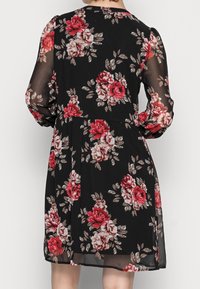 Schwarzes Blumenkleid mit roten und rosa Rosenmustern, langen transparenten Ärmeln, rundem Ausschnitt und tailliertem Schnitt, mit einem fließenden Rock.