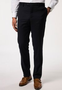 Pantalones navy hechos de una tela suave, con un diseño de frente plano, bolsillos laterales y pasadores para cinturón, combinados con zapatos de doble hebilla marrones.