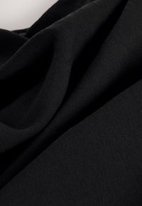 Tissu noir avec des plis doux et une texture lisse, montrant des détails en gros plan du matériau tissé.