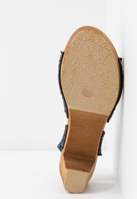 Semelle de sandale montrant un dessous en caoutchouc beige texturé, un talon en bois, et la taille 37 marquée dans un ovale.