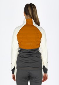 Letvægtsjakke med en cremefarvet overflade, orange øvre ryg og grå nederste sektion. Høj krave og tætsiddende design med stretchstof.