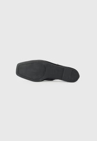 Black shoe sole with a smooth rubber texture, featuring a slight pattern for grip. The shape is slightly rounded at the toe and heel.