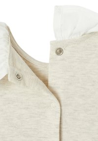 Hellbeige Baumwolloberteil mit gerüschtem weißen Kragen, Druckknopfverschlüssen und einer weichen, strukturierten Oberfläche sowie einem Rundhalsausschnitt.
