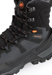 Black and gray hiking boot featuring textured fabric, lacing system with orange accents, and a rugged sole. Branded with "Mammut" and "Drytechnology."