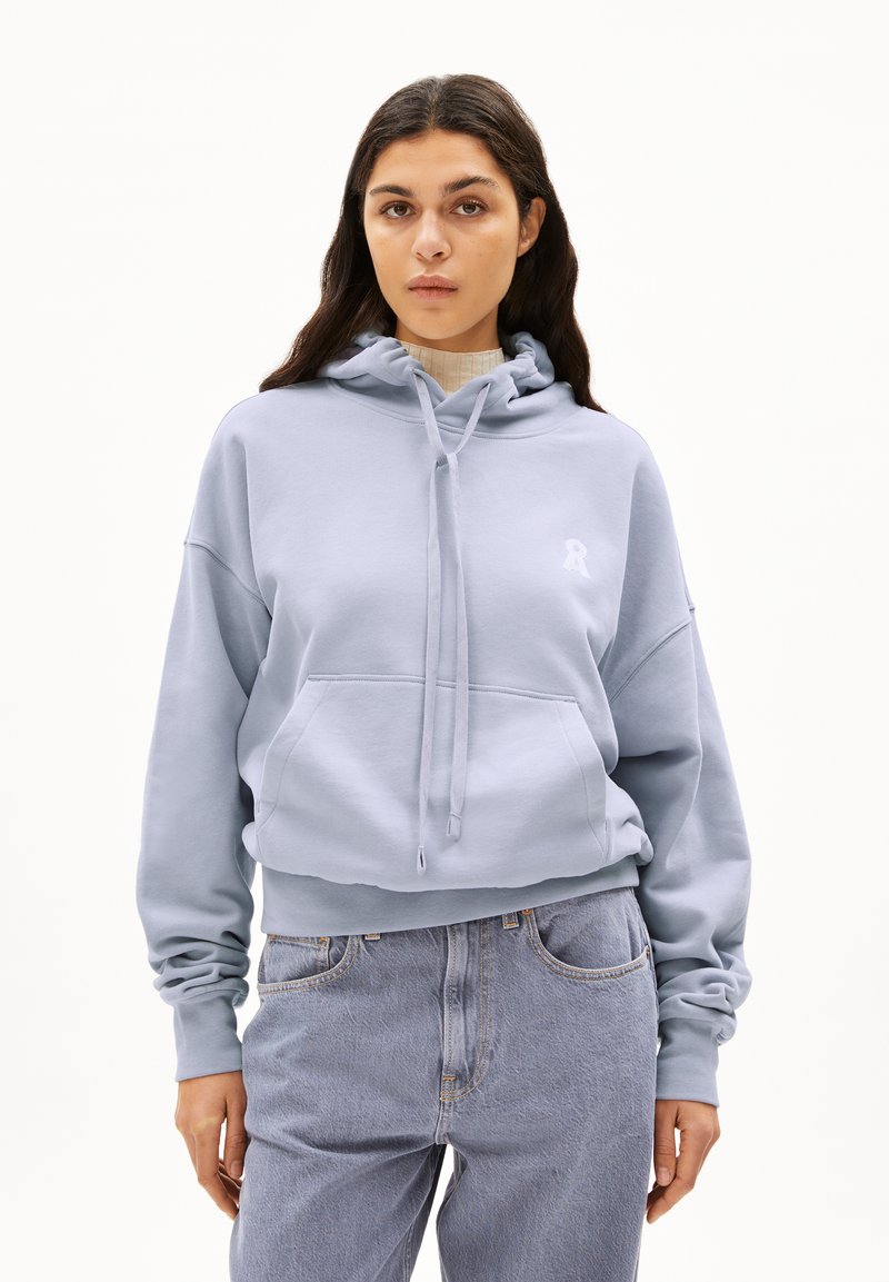 Lichtblauwe cropped hoodie met een trekkoord, een voorkantvak en een wit logo op de borst. Gemaakt van zachte, gestructureerde stof. In combinatie met lichtdenim jeans.