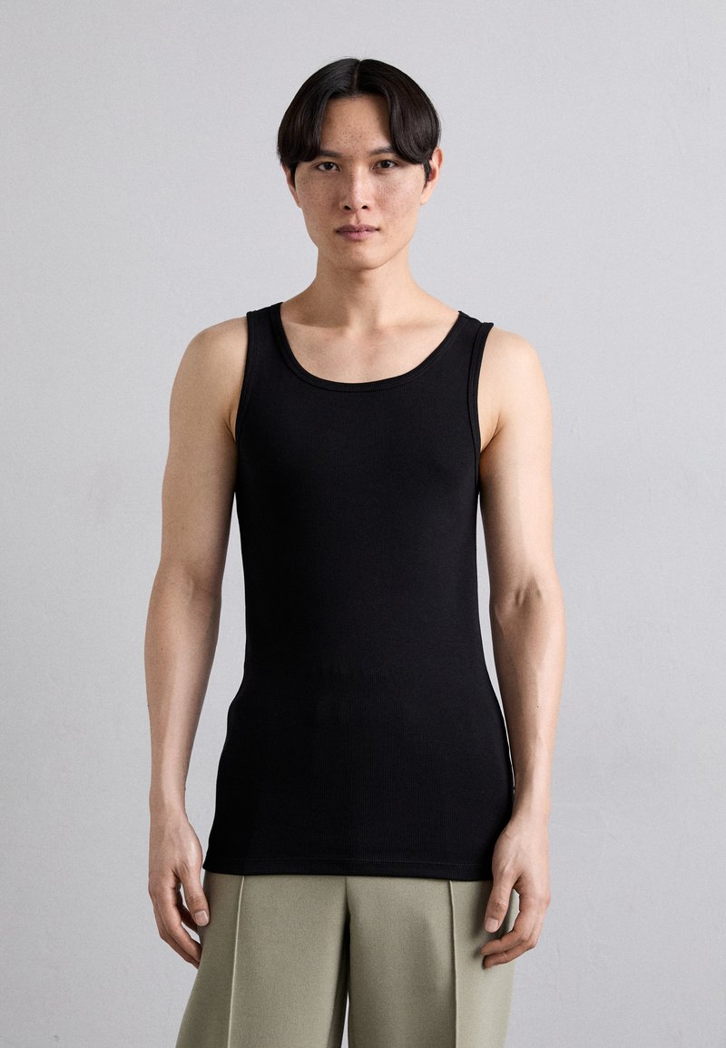 Must mustriba tank top ümmarguse kaelusega, omab sobivat disaini ja sujuvaid õlapaelu. Materjal näib olevat pehme ja veniv.