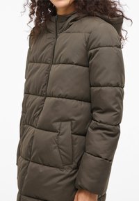 Gewatteerde jas in olijfgroen met een doorgestikt ontwerp, capuchon en ritssluiting. Voorzien van zijzakken en een gladde, licht glanzende textuur.