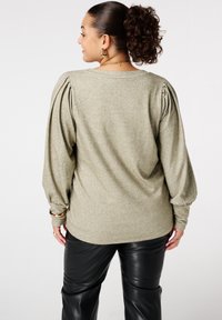 Licht olijfgroen sweater met pofmouwen, textuur gebreide stof en een relaxte pasvorm. Gepaard met zwarte kunstlederen broek.
