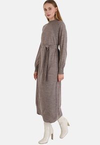 Neulemekko pitkillä hihoilla taupe-värissä, korkea kaula-aukko, vyö vyötäröllä ja ribbireunukset hihoissa ja sivuissa.