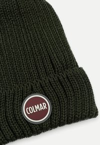 Tumšzaļš adīts beanie cepure ar ribotu tekstūru un apļa logotipa uzšuvi maroon, baltā un pelēkā krāsā, kurā ir vārds "COLMAR."