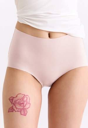 Unterer Rumpf einer Person, die nahtlose Unterwäsche in Hellrosa trägt, mit einem roten Rosen-Tattoo am oberen linken Oberschenkel sichtbar.