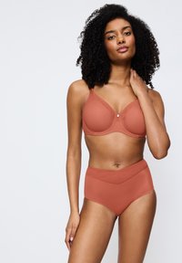 Bralette en hooggetailleerde briefset in terracotta. Zachte, naadloze stof met een gladde afwerking, voorzien van verstelbare bandjes en een subtiel taillebandontwerp.