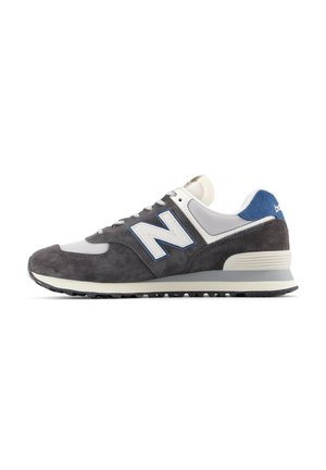 Herren-Sneaker aus grauem Wildleder mit weißen und blauen Akzenten, ausgestattet mit einer gepolsterten Sohle, Schnürverschluss und einem großen "N"-Logo an der Seite.