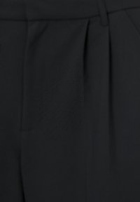 Czarna tkanina z lekko innym teksturowanym naszywką przyszytą na powierzchni w pobliżu pasa i zaszewki.