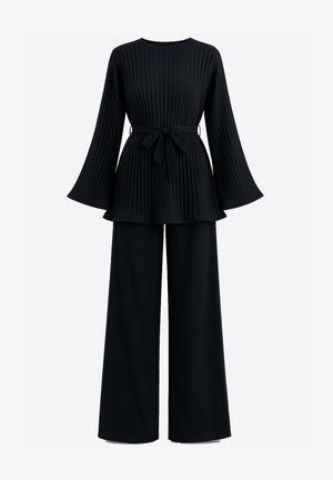 Top nero plissettato con maniche svasate e cintura in vita, abbinato a pantaloni a gamba larga. Realizzato in un tessuto liscio con una finitura strutturata.