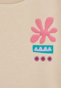 Beige audums ar abstraktu ziedu dizainu, kas ietver lielu rozā ziedlapu formu, teāla taisnstūri ar purpura zigzagiem un trim mazām purpura zvaigznītēm.