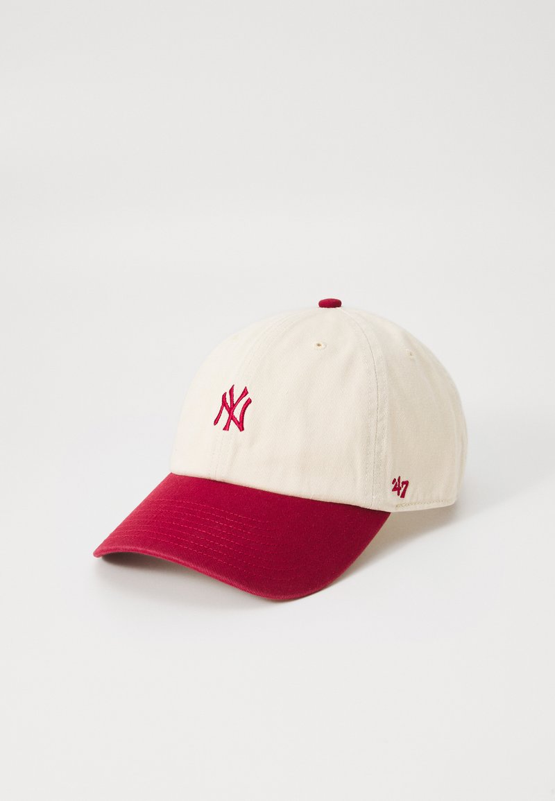 Beige baseball cap i bomull med en rød skjerm. Har brodert NY-logo og 47-merke på siden. Strukturert form med ventilasjonshull.