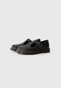 Pantofi negri din piele cu vârf rotund, având o cataramă pe lateral și un design decupat. Talpa groasă neagră are un accent de cusătură galbenă.