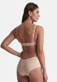 Lichtbeige beha met verstelbare schouderbanden en een haak-en-oogsluiting op de rug, gecombineerd met bijpassende naadloze high-waisted onderbroek.