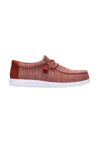 Chaussure décontractée à enfiler en tissu rouge texturé avec détail de lacets et semelle blanche tachetée, vue latérale sur fond blanc.