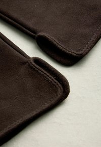 Brown suede pads with rounded edges and stitching detail, resting on a light surface, showcasing soft texture and sleek design.