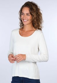 Langärmliges Oberteil in Creme mit Rundhalsausschnitt und Spitzendetails am Kragen und den Ärmelbündchen, aus einem weichen, leichten Stoff.