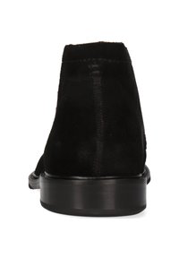 Stivaletto in suede nero con punta rotonda, cuciture lisce e tacco basso impilato. La suola è lucida, offrendo un contrasto con la tomaia opaca.