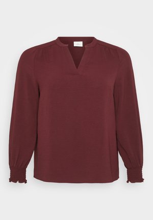 Burgundy blouse with long sleeves, V-neckline, pleated details at shoulders, and smocked cuffs. Made from textured, lightweight fabric.