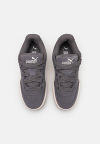 Chaussures de sport grises en suède et mesh, avec un col rembourré, un système de laçage et une semelle en caoutchouc de couleur claire.