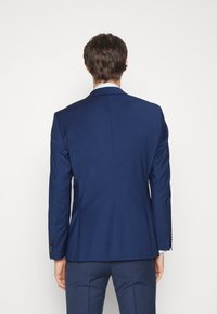 Sacou ajustat de culoare albastru marin, cu fante unice, croială slim fit și închidere cu două nasturi. Material texturat, design minimalist și mansete cu nasturi.
