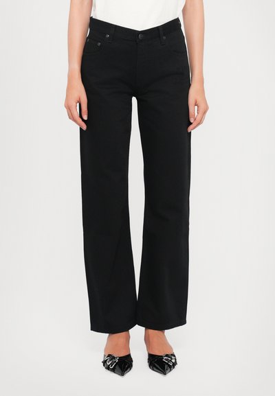 Sorte brede jeans lavet af denim, med en kraftig talje, frontlommer og diskret branding på siden. Glat tekstur.