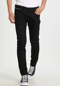Černé džíny z denimu se slim fit, s kapsami na zip a prošívanými akcenty. Kombinované s černobílými teniskami.