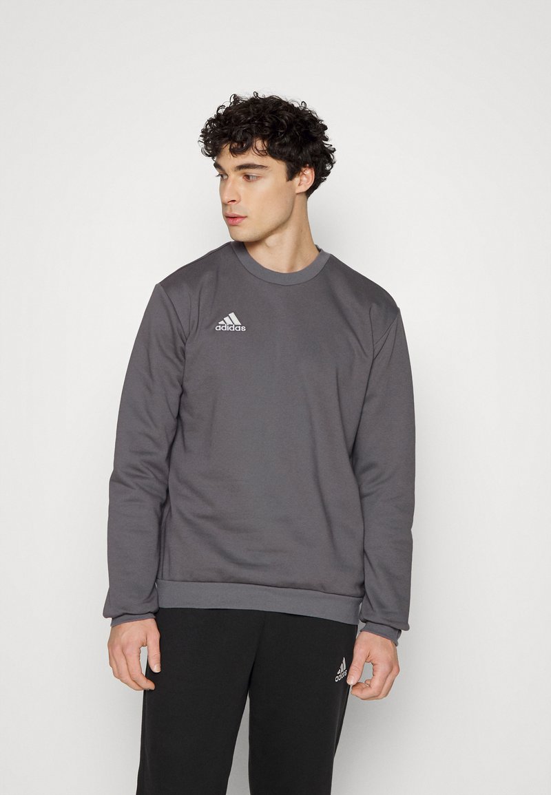 Grå sweatshirt lavet af en blanding af bomuld, med rund halsudskæring og ribbede manchetter. Pyntet med et lille hvidt Adidas-logo på brystet.