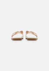 Nude gelé-sandaler med platt sula, öppen tå-design och urtagsmönster på ovandelen. Gummimaterial med en slät textur.
