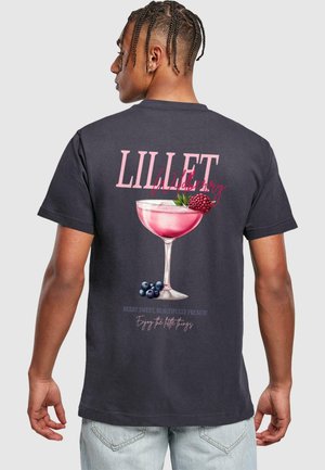 Sort T-shirt med en farverig cocktailglas grafik, der viser pink væske, bær og teksten "LILLET Wildberry" i fede hvide og pink skrifttyper.