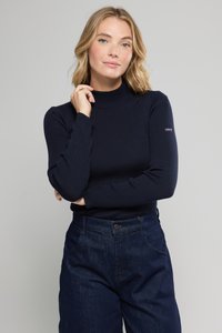 Pullover a collo alto a coste di colore blu navy, design aderente, maniche lunghe e una patch con logo sulla parte superiore del braccio, abbinato a pantaloni in denim blu a vita alta.