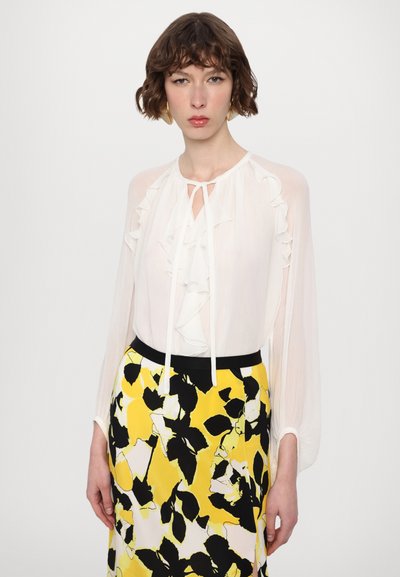White ruffled blouse with a tie neckline paired with a black and yellow floral print pencil skirt. Smooth texture, long sleeves, contrasting patterns.