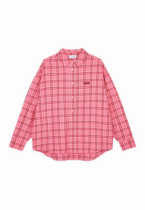 Roze geruit overhemd met lange mouwen, een kraag en knoopsluiting. Heeft donkerdere lijnen en een klein merklapje aan de voorkant.