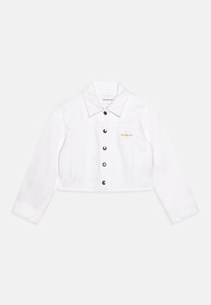 Veste courte en denim blanc avec manches longues, fermeture par boutons sur le devant, col et petit logo doré « Calvin Klein Jeans » sur la poitrine gauche.