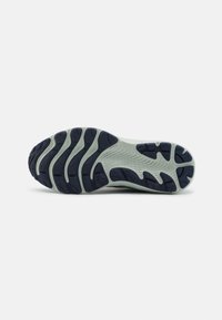 Semelle d'une basket avec un motif de bande de roulement rainuré noir sur une base gris clair, conçue pour la traction et la flexibilité.
