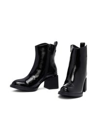 Botas negras hasta el tobillo con acabado en charol, con tacón cuadrado, cremallera lateral y superficie texturizada. Bordes lisos y acentos mínimos.