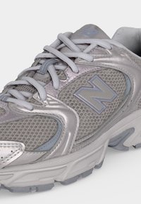 Γκρι αθλητικό παπούτσι New Balance με επάνω μέρος από πλέγμα και συνθετικό υλικό, δεμένα κορδόνια και παχύ, μαλακό πέλμα.