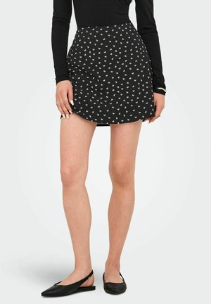 Sort mini skirt med hvidt blomsterprint, med en tætsiddende pasform og glat tekstur. Parret med sorte slingback flade sko.